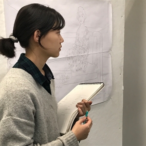 一名学生一边做笔记,一边检查一件艺术品。