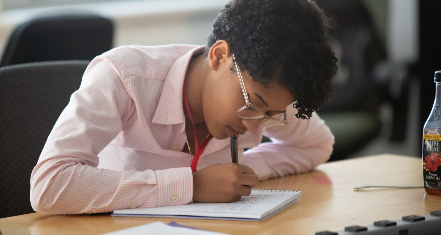 一个学生在他们书桌上的笔记本上写字
