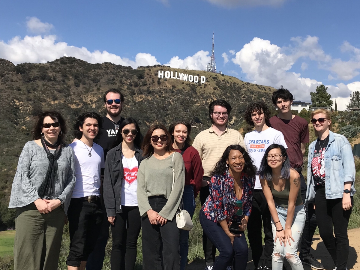 学生和教师在他们的洛杉矶，加利福尼亚州的旅行期间在好莱坞标志前面的一张照片的姿势。