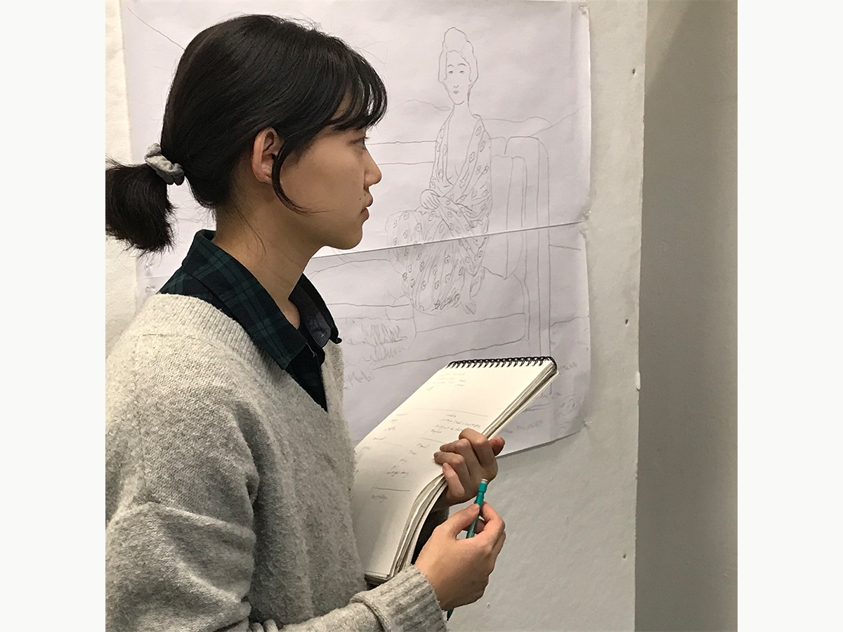 一名学生一边做笔记，一边检查一件艺术品。