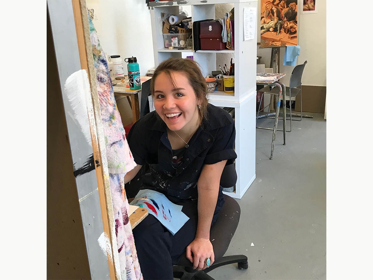 一名学生在绘画工作室工作时在镜头上微笑。
