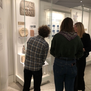两个学生一边听导游讲解，一边看宾州博物馆的一件文物。