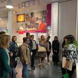 学生聚集在史密森尼国家自然历史博物馆的化石展览中的旅游指南周围