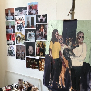 一个学生的工作室，墙上贴着图片，画架上挂着一幅正在创作的作品。